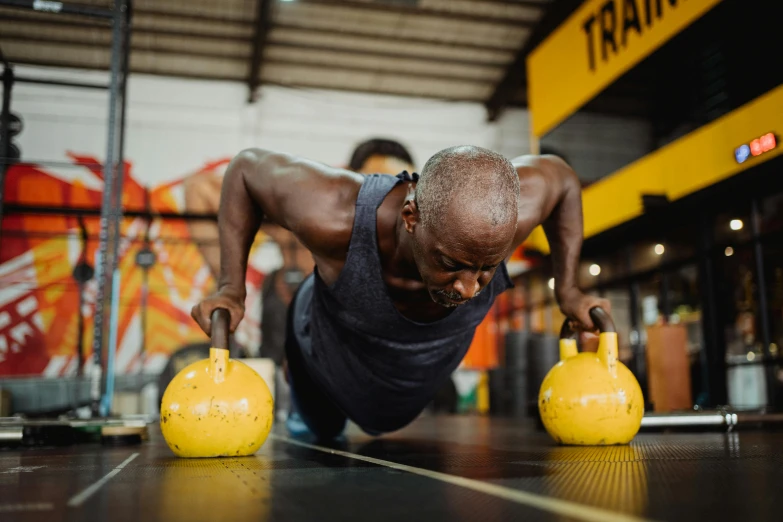 a man doing push ups on a yellow kettle, pexels contest winner, man is with black skin, old man doing hard work, local gym, 🦩🪐🐞👩🏻🦳