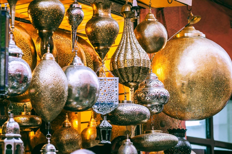 a bunch of lamps hanging from a ceiling, a photo, by Julia Pishtar, trending on unsplash, arabesque, draped in shiny gold and silver, market stalls, slightly tanned, youtube thumbnail
