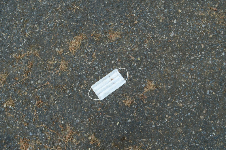 a white face mask laying on the ground, by Attila Meszlenyi, postminimalism, miscellaneous objects, small, roadside, rectangle