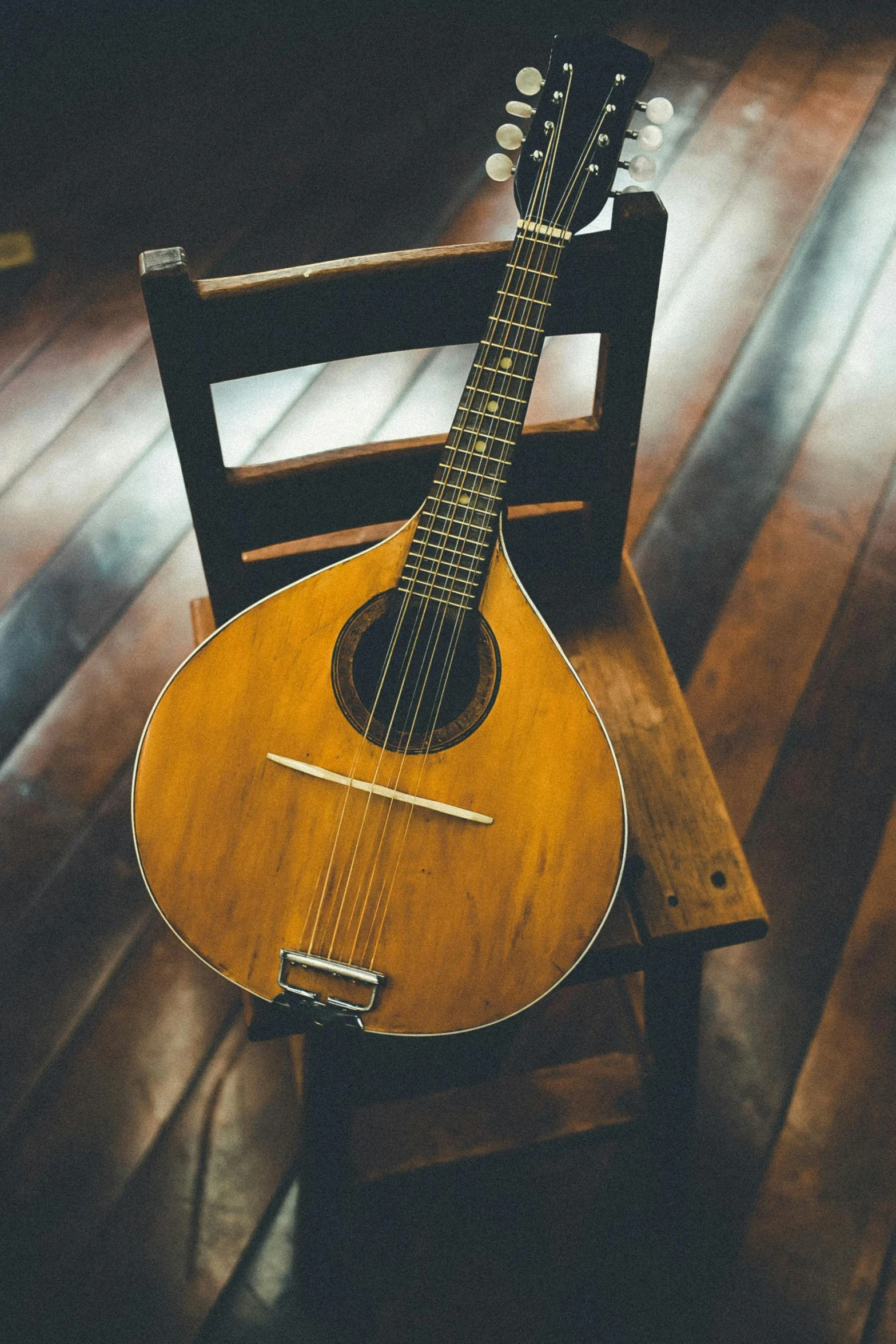 a guitar sitting on top of a wooden chair, playing a mandolin, on a table