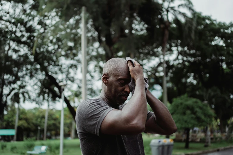 a man holding his head in his hands, by Matija Jama, pexels contest winner, in a park, lance reddick, sweating hard, caring fatherly wide forehead