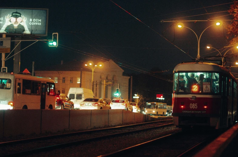 a red and white train traveling down train tracks, by Attila Meszlenyi, happening, night street, public bus, 2000s photo, high quality picture