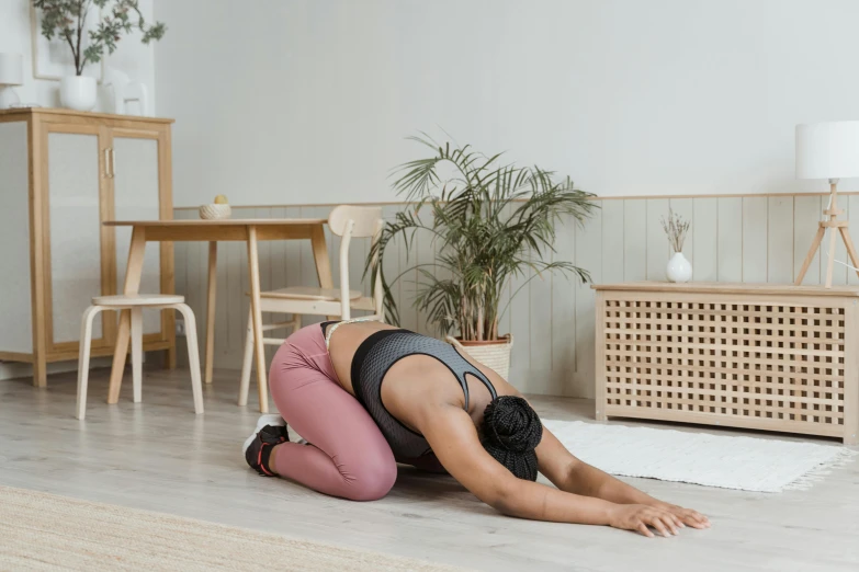 a woman is doing a yoga pose on the floor, by Emma Andijewska, hurufiyya, bent over, on a table, manuka, profile image