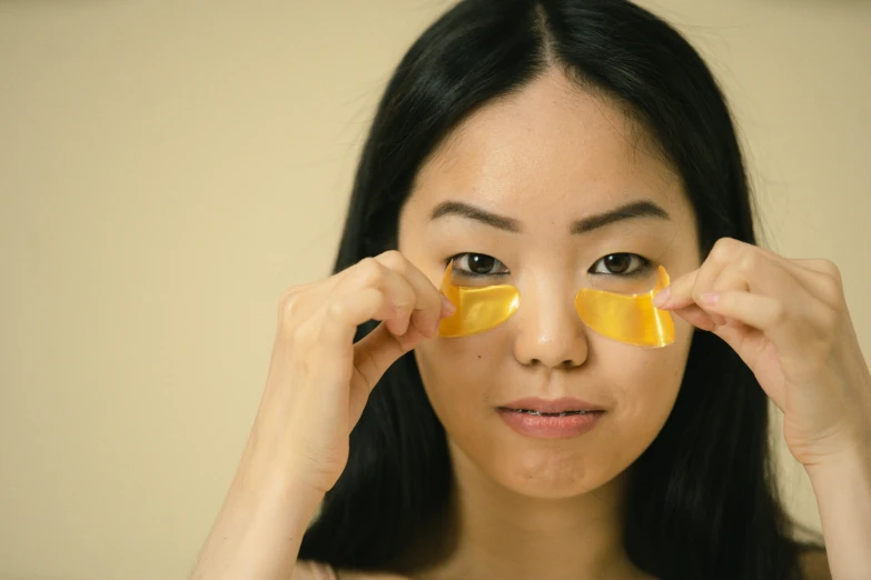 a woman with an orange peel on her face, trending on pexels, mingei, wearing gold glasses, japanese collection product, wearing translucent sheet, frontal shot