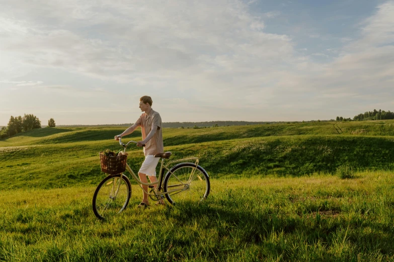 a man riding a bike through a lush green field, pexels contest winner, late afternoon sun, avatar image, midsommar, exterior shot