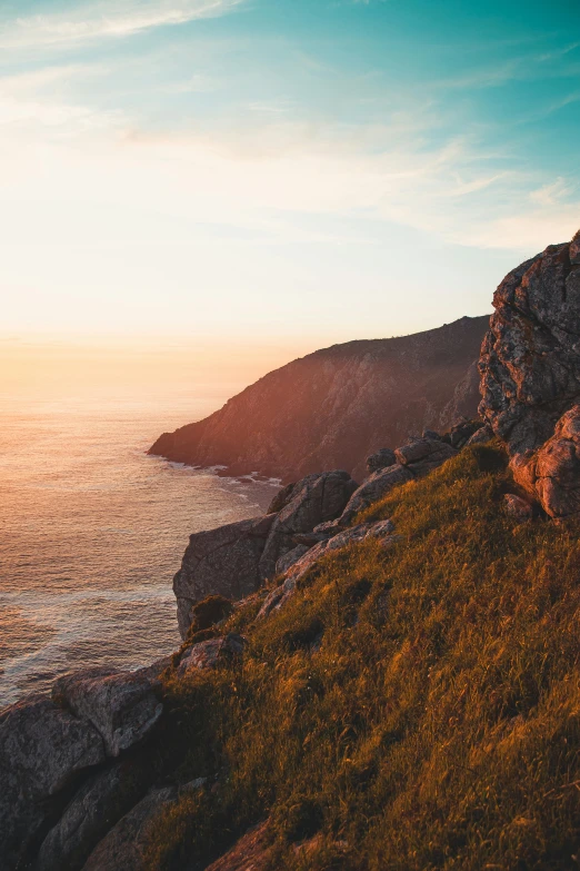 a person standing on a cliff overlooking the ocean, by Daniel Lieske, pexels contest winner, sunset panorama, large cape, color graded, lush surroundings