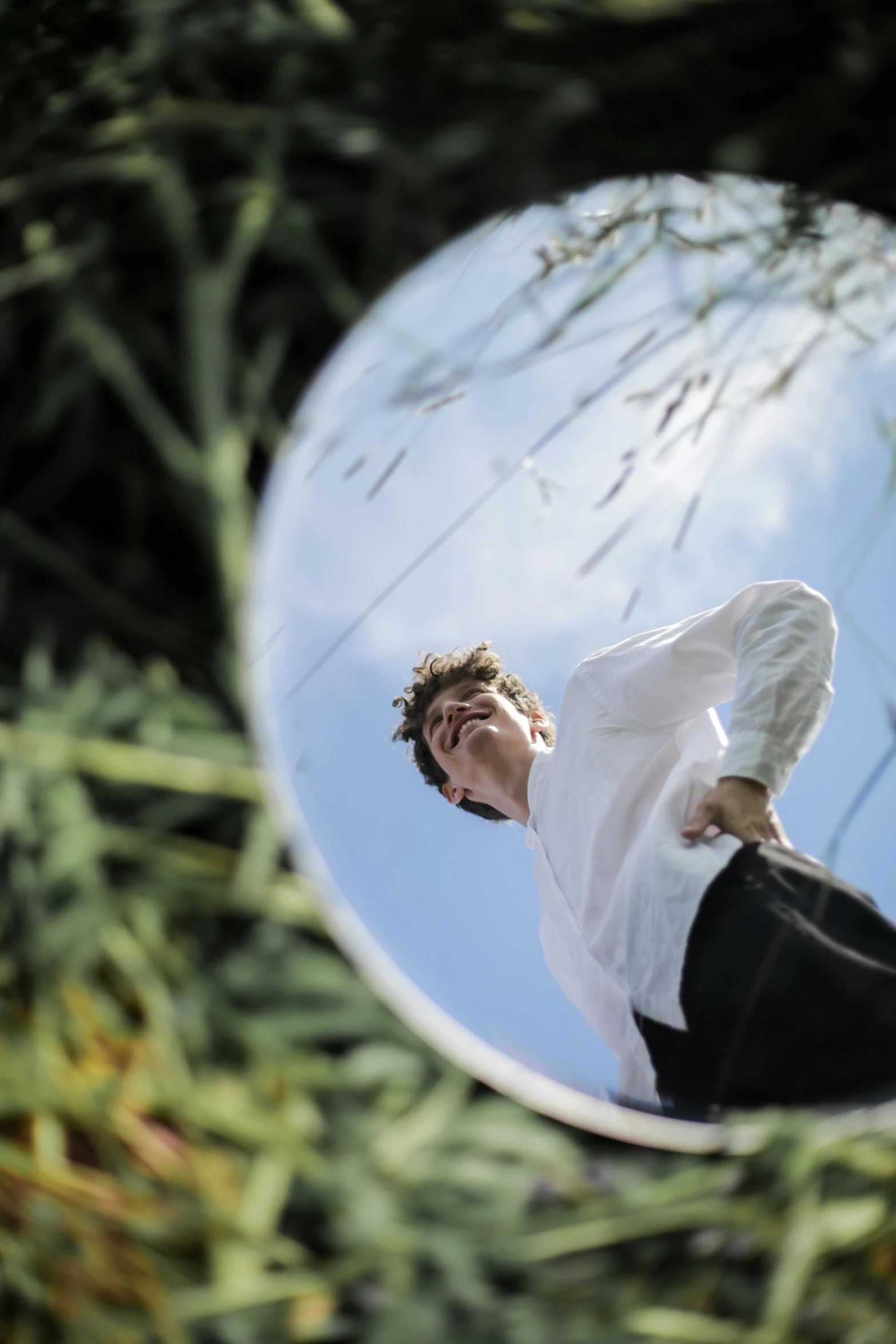 a man in a white shirt is reflected in a mirror, an album cover, by Jacob Toorenvliet, levitating agricultural sphere, on a sunny day, low angle photograph, high angle shot