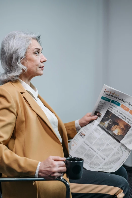 a woman sitting in a chair reading a newspaper, trending on reddit, gray haired, professional photo, in the center of the image, business woman