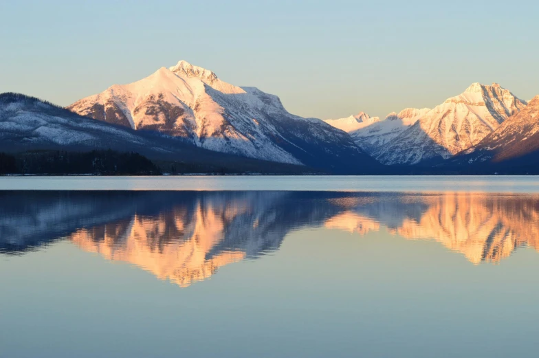 a large body of water with mountains in the background, by Jim Nelson, pexels contest winner, winter vibrancy, reflective light, montana, brittney lee
