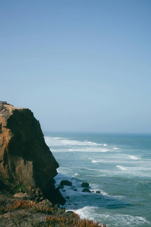 a man standing on top of a cliff next to the ocean, by Jacob Burck, telephoto vacation picture, san francisco, may)