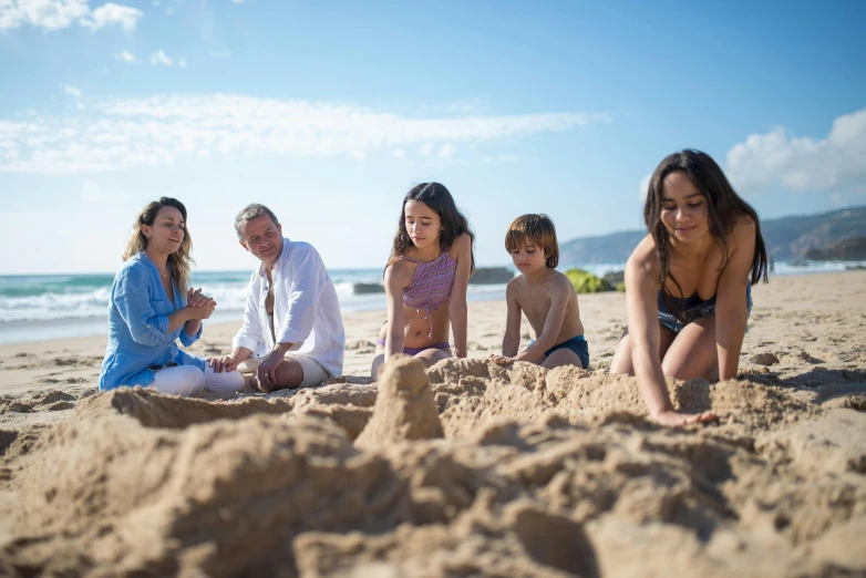 a group of people sitting on top of a sandy beach, on the sand, sandcastle, beach on the outer rim, moana