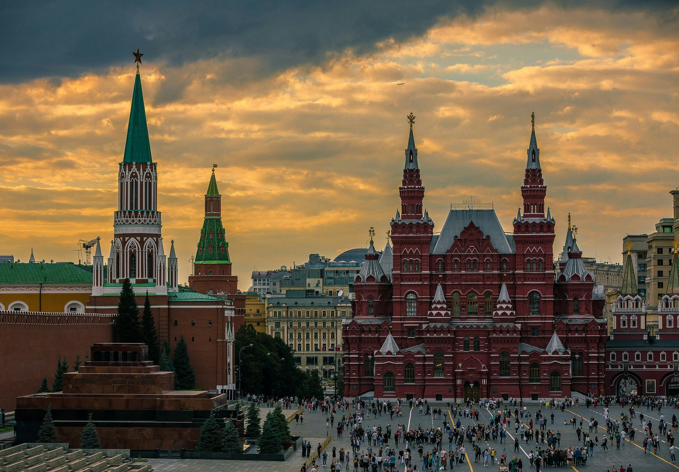 a group of people that are standing in front of a building, inspired by Vasily Surikov, pexels contest winner, socialist realism, at dusk, green and red, square, travel guide