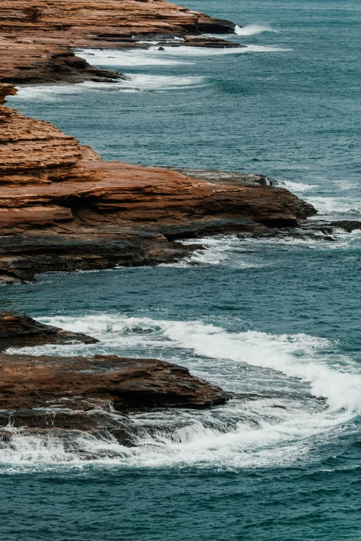 a group of people standing on top of a cliff next to the ocean, pexels contest winner, australian tonalism, staggered terraces, blue crashing waves, sandstone, middle close up