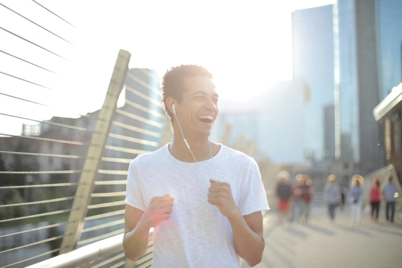 a young man listening to music on a bridge, pexels contest winner, happening, earing a shirt laughing, people running, lean man with light tan skin, health supporter