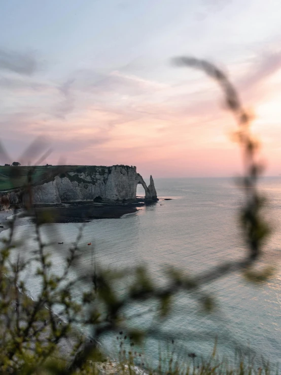 a large body of water next to a cliff, by Raphaël Collin, pexels contest winner, romanticism, northern france, at sunrise in springtime, slide show, 2022 photograph