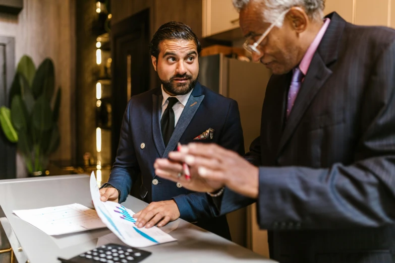 a couple of men standing next to each other, a photo, by Matt Cavotta, pexels contest winner, renaissance, business meeting, at the counter, wearing a colorful men's suit, a portrait of rahul kohli