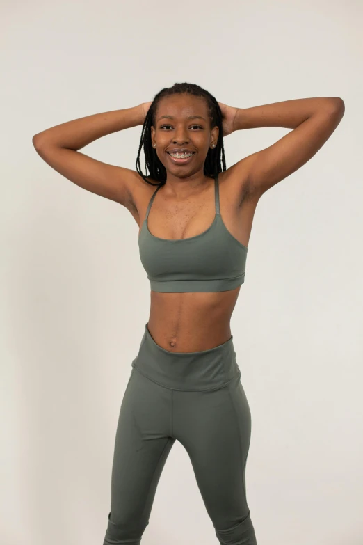 a woman in a sports bra top and leggings, by Ella Guru, muted green, satisfied pose, upper body image, wearing a cropped tops