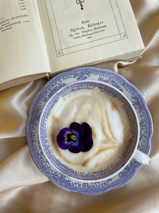 a book sitting on top of a bed next to a cup of coffee, inspired by Violet Fuller, renaissance, edible flowers, creamy skin, profile pic, soup