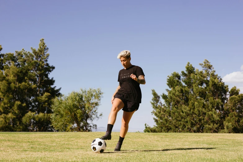 a woman kicking a soccer ball on a field, unsplash, realism, short platinum hair tomboy, lachlan bailey, wearing black shorts, outlive streetwear collection