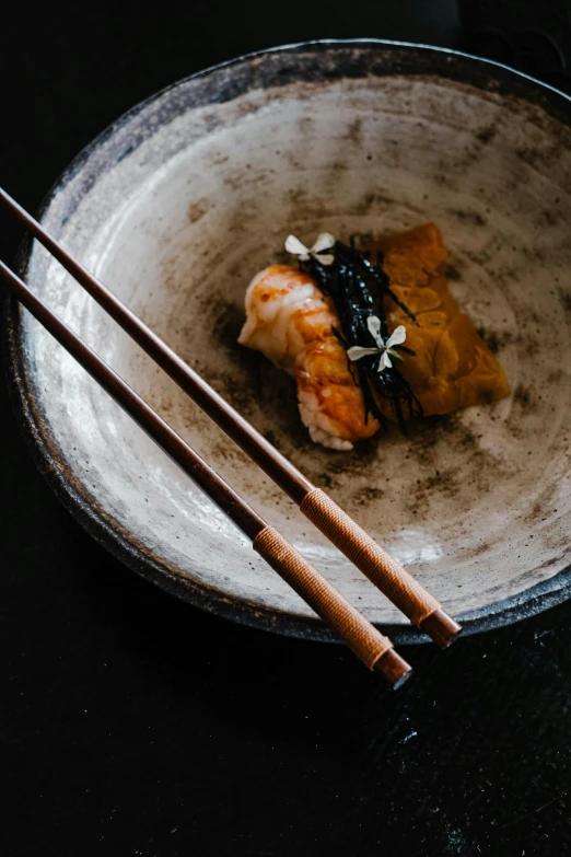 a close up of a plate of food with chopsticks, a portrait, unsplash, mingei, black and terracotta, square, koi, woodfired