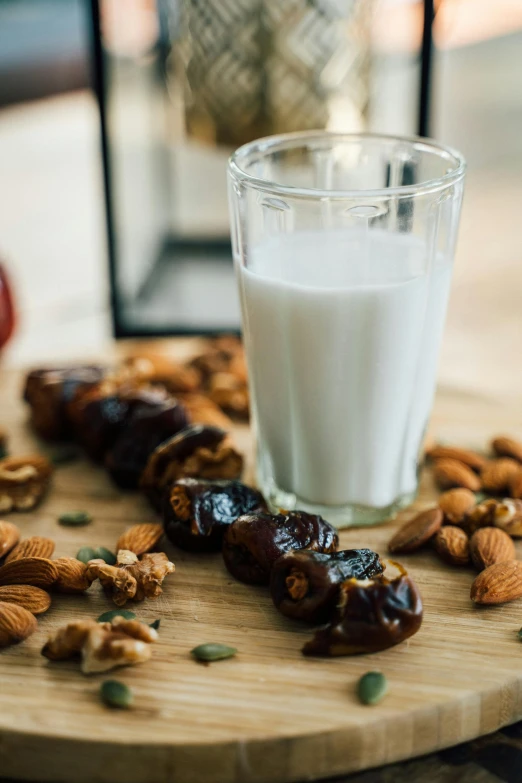 a glass of milk sitting on top of a wooden cutting board, by Julia Pishtar, renaissance, middle eastern, nut, snacks, profile image