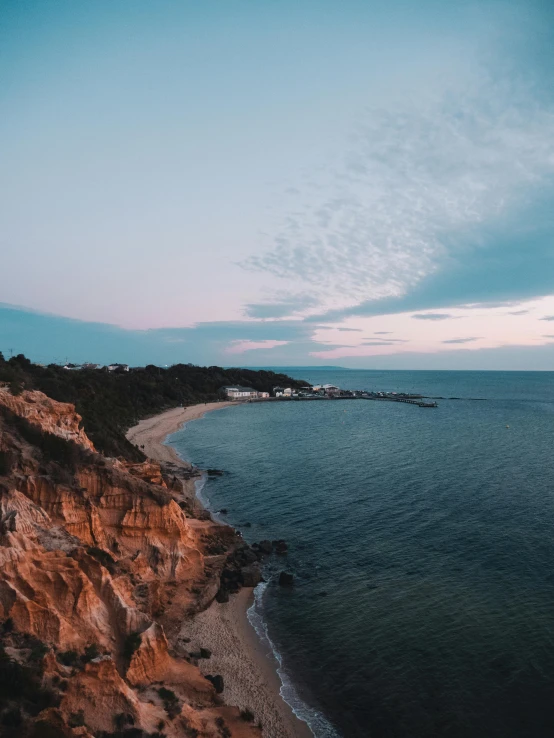 a person standing on top of a cliff next to the ocean, craigville, today\'s featured photograph 4k, evening lights, wide overhead shot