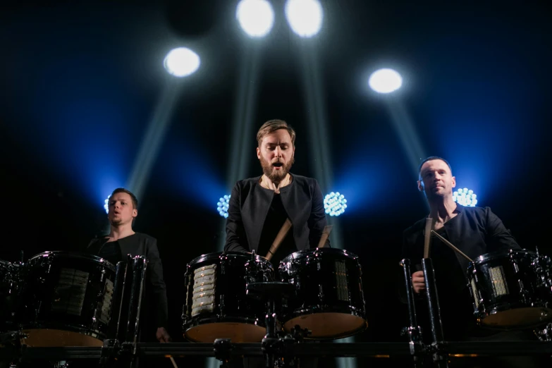 a group of men standing next to each other on top of a stage, inspired by Ásgrímur Jónsson, purism, drum kit, portrait image, deep black, trio