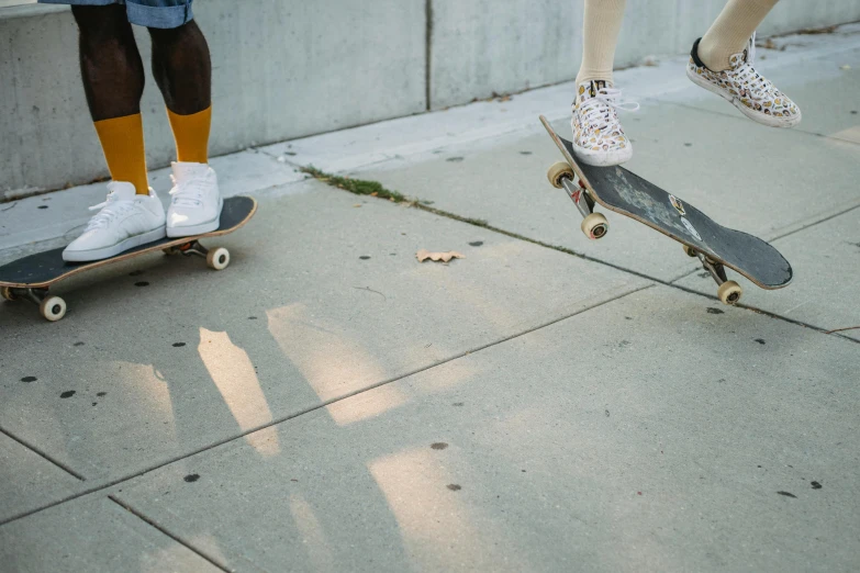 a couple of people riding skateboards on a sidewalk, trending on unsplash, realism, detailed shot legs-up, kids playing, low quality photo, harriet tubman skateboarding