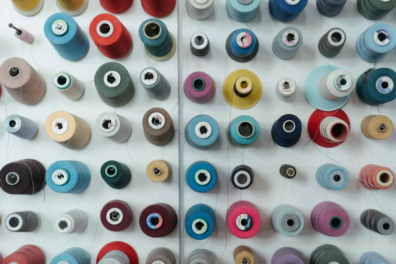 a number of spools of thread on a table, unsplash, a portrait of issey miyake, 15081959 21121991 01012000 4k, thumbnail, white wall coloured workshop