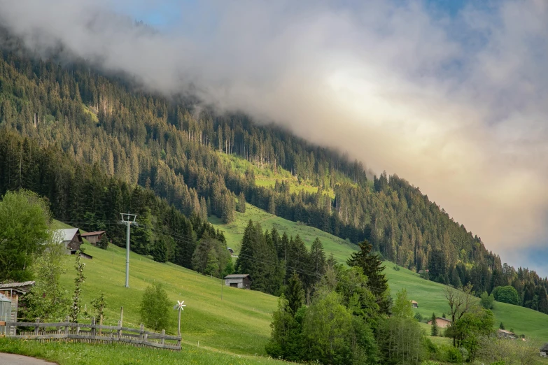 a car driving down a road next to a lush green hillside, by Sebastian Spreng, pexels contest winner, renaissance, log cabin beneath the alps, chairlifts, soft morning light, panorama