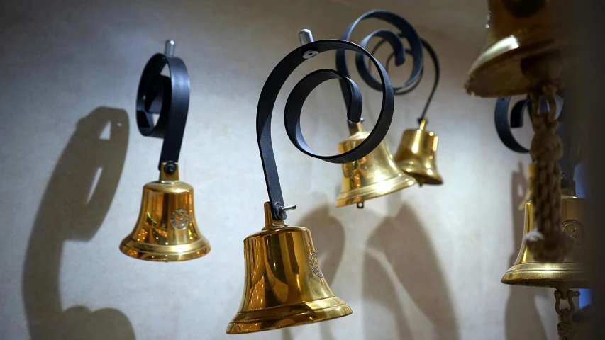 a bunch of bells hanging on a wall, an album cover, pixabay, baroque, hotel room, gold and black metal, museum light, bespoke