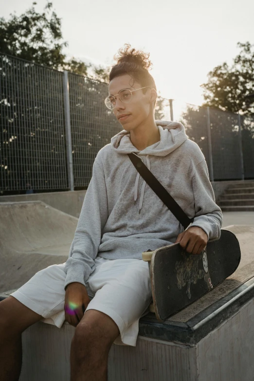 a young man sitting on a ledge with a skateboard, trending on unsplash, an epic non - binary model, white clothing, profile image, sun behind her