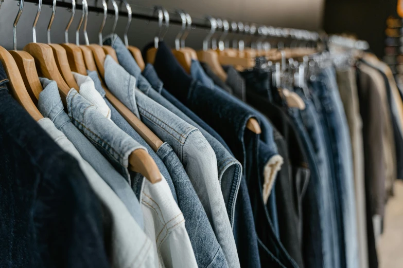 clothes hanging on a rack in a clothing store, by Carey Morris, trending on unsplash, wearing double denim, blue and grey tones, federation clothing, wearing a jeans jackets