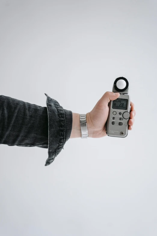 a person holding a remote control in their hand, by Matthias Stom, trending on pexels, minimalism, ring light, holding a pocket watch, monocular, grey