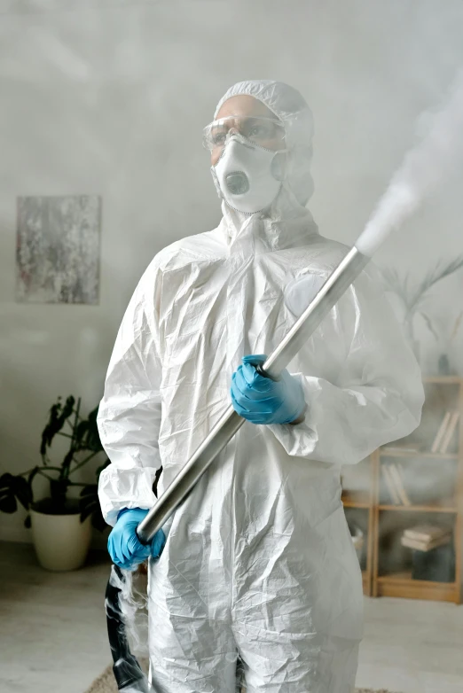 a man in a protective suit sprays down a room, a portrait, pexels contest winner, holding a thick staff, profile image, robe, thumbnail