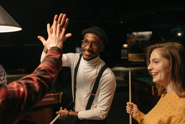 a group of people standing around a pool table, pexels contest winner, happening, waving arms, black man, promotional image, holding a staff