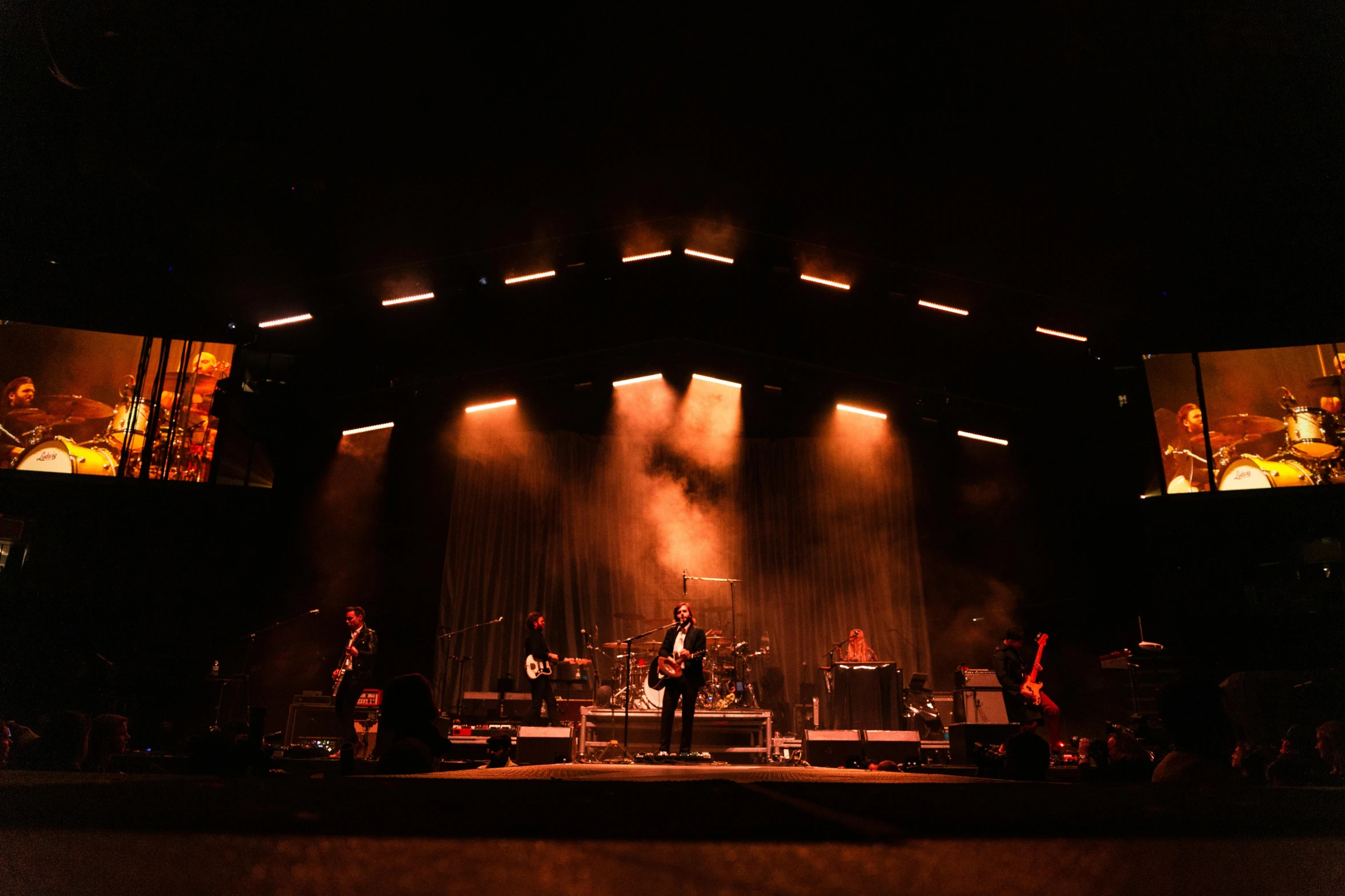 a group of people standing on top of a stage, hozier, lights in the dark, playing guitar onstage, profile image