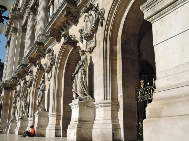 a person sitting on a bench in front of a building, a marble sculpture, inspired by Stanislas Lépine, pexels contest winner, there are archways, palace of the chalice, high level of detail, looking to the right