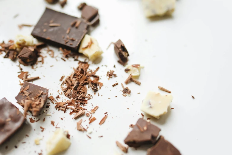 a white plate topped with pieces of chocolate, by Daniel Lieske, trending on unsplash, on a pale background, crushed, cheesy, brunette