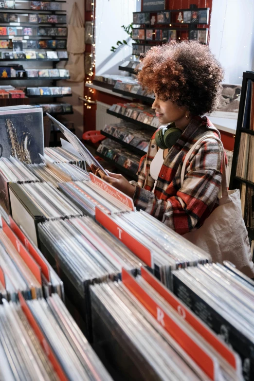 a woman looking at records in a record store, trending on pexels, seasonal, thumbnail, brown, low quality photo