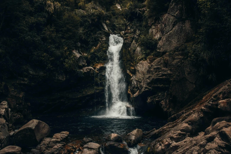 a waterfall in the middle of a lush green forest, by Elsa Bleda, unsplash contest winner, australian tonalism, on a dark rock background, lakes and waterfalls, 2000s photo, vacation photo