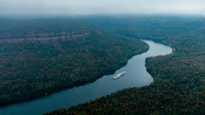 a large boat traveling down a river next to a forest, by Dan Frazier, pexels contest winner, hudson river school, aerial view cinestill 800t 18mm, alabama, sheer cliffs surround the scene, panorama