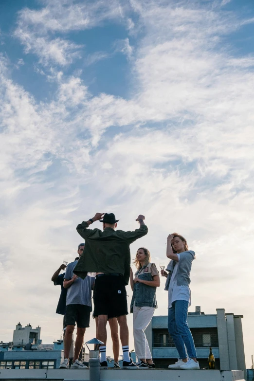 a group of people standing on top of a roof, by Niko Henrichon, unsplash, happening, dabbing, manly, low quality photo, skies