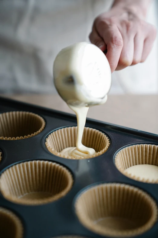 a person pouring batter into a muffin tin, by Glennray Tutor, trending on unsplash, square, made of glazed, vanilla, 8l