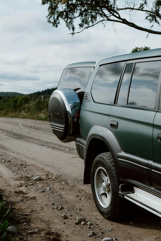 a green suv parked on the side of a dirt road, pexels contest winner, photorealism, 1990s, looking from behind, steel gray body, travellers