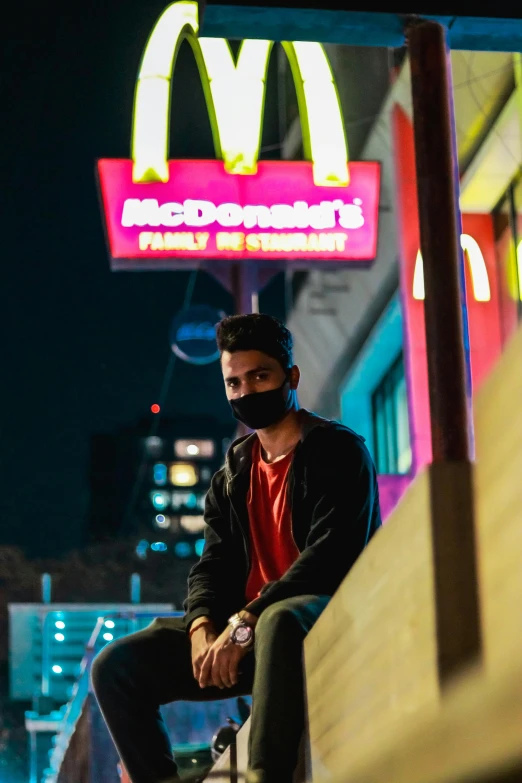 a man sitting on a bench in front of a mcdonald's sign, an album cover, trending on pexels, elaborate lights. mask on face, david marquez, jc park, on rooftop