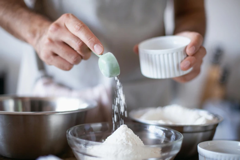 a person is sprinkling flour into a bowl, inspired by Yukimasa Ida, trending on pexels, close up of single sugar crystal, epicurious, best practice, basil gogos