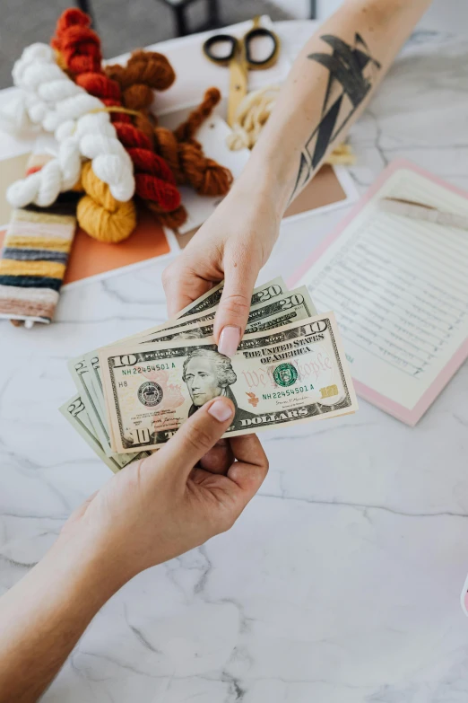 a person handing money to another person at a table, a cross stitch, pexels contest winner, stuffed animal, photo of a model, curated collections, julia sarda