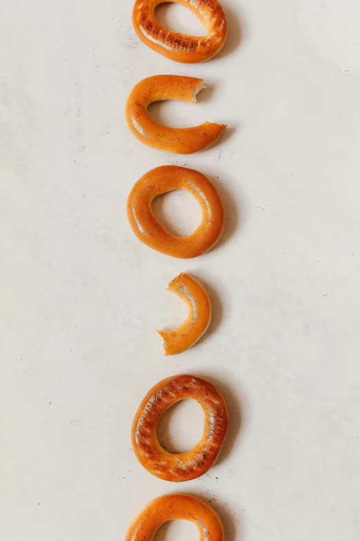 a number of pretzels on a white surface, by Ben Zoeller, orange halo, enso, ignant, smooth matte