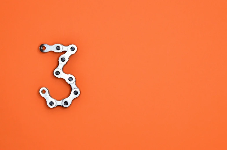 a close up of a bicycle chain on an orange background, inspired by Lubin Baugin, unsplash, number 31!!!!!, ffffound, giant threes, made from mechanical parts